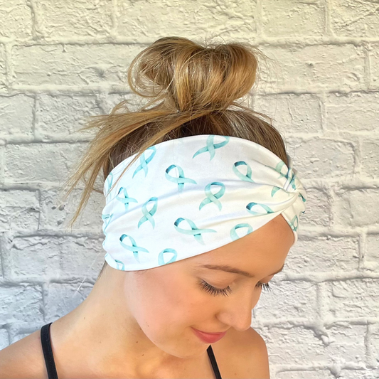 Woman with hair in bun wearing wide, white, twisted headband with light blue ribbon print.