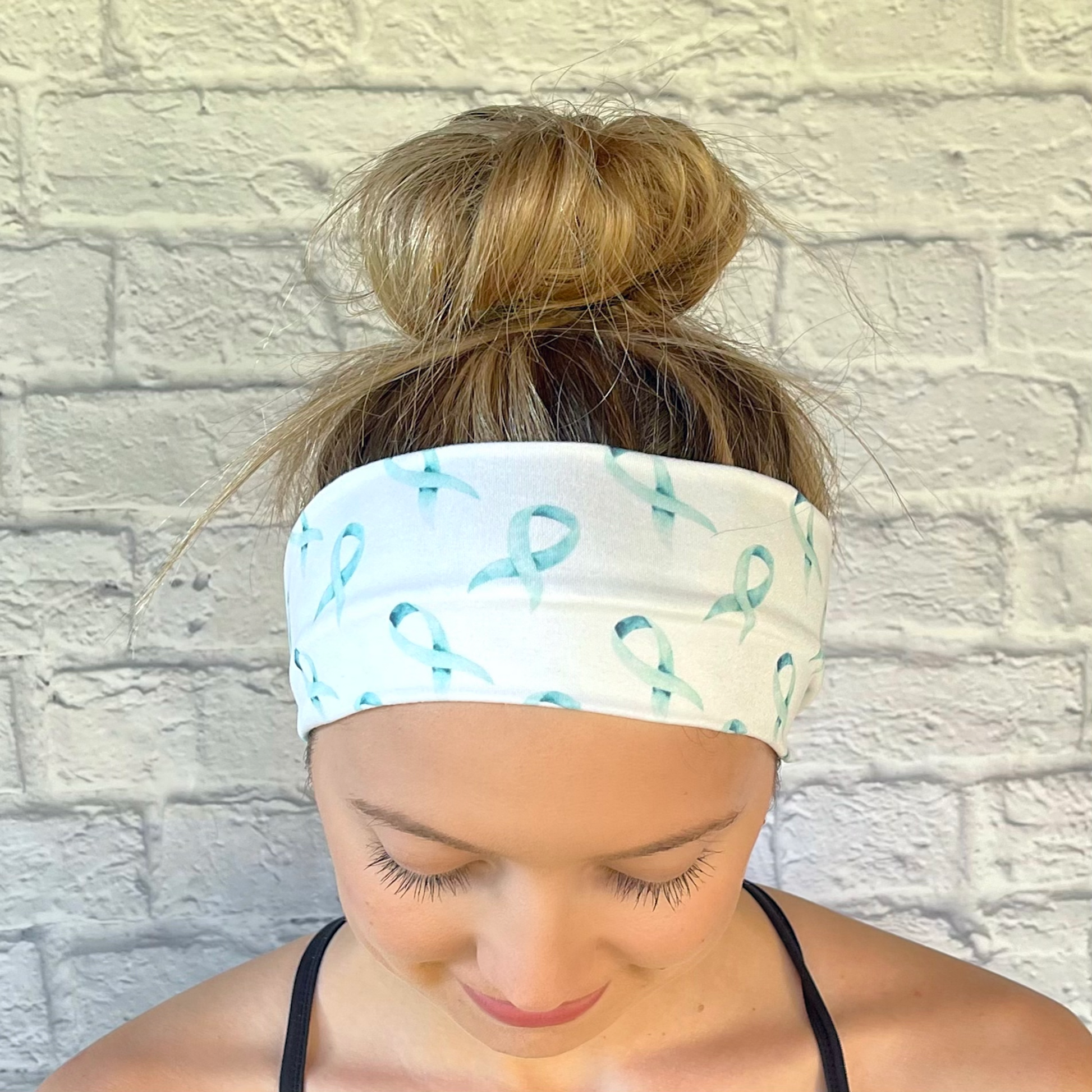 Woman with hair in bun wearing white headband with light blue ribbons print.