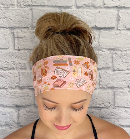 Woman with hair in bun wearing stretchy, light pink headband with book and flower print.