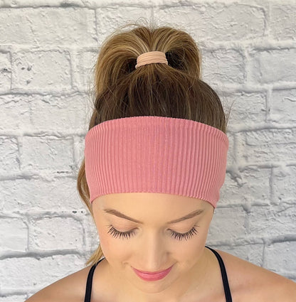 Woman with hair in curled ponytail wearing flat, stretchy, pink ribbed headband.