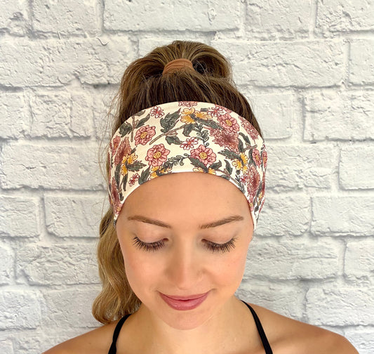 Woman with hair in ponytail wearing flat, stretchy headband in white with pink and yellow flower print.