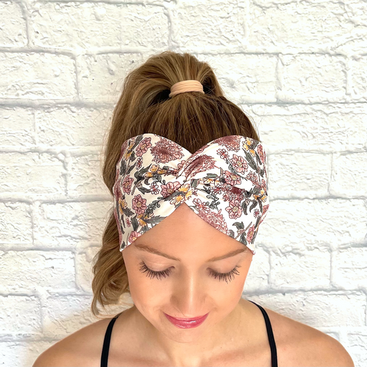 Woman with hair in ponytail wearing wide, white headband with pink and yellow flowers.