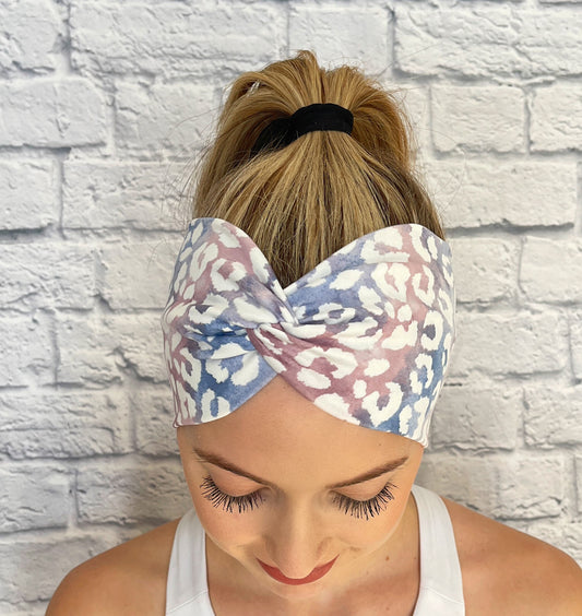 Woman with hair in ponytail wearing wide, twisted headband in purple, blue, and white cheetah print.