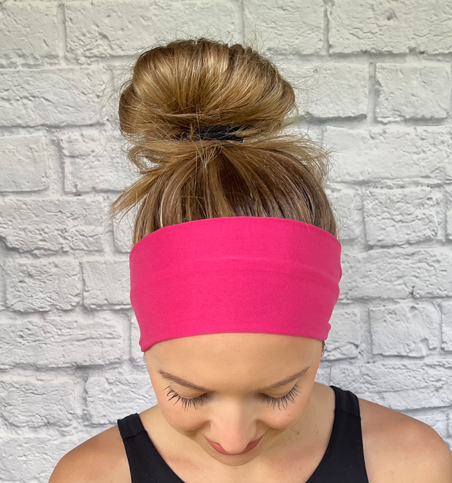 Woman with hair in bun wearing flat, stretchy, bright pink headband.