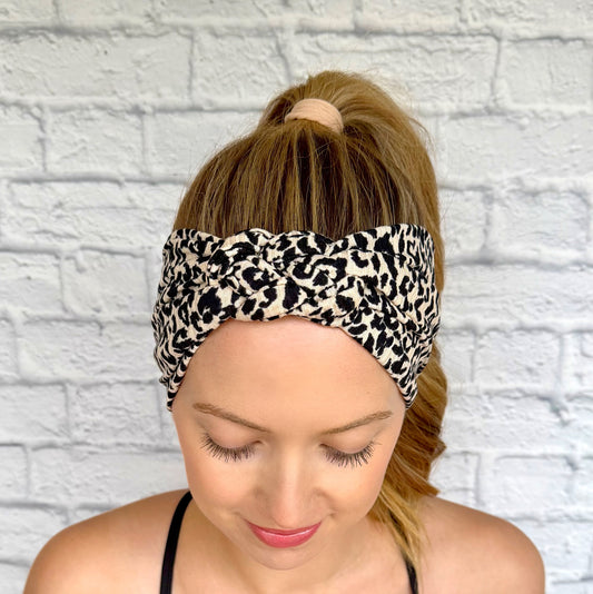 Woman with hair in curled ponytail wearing tan/cream color with black leopard print headband in sailor knot style.