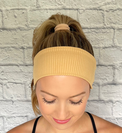 Woman with hair in curled ponytail wearing flat, stretchy, tan color ribbed headband.