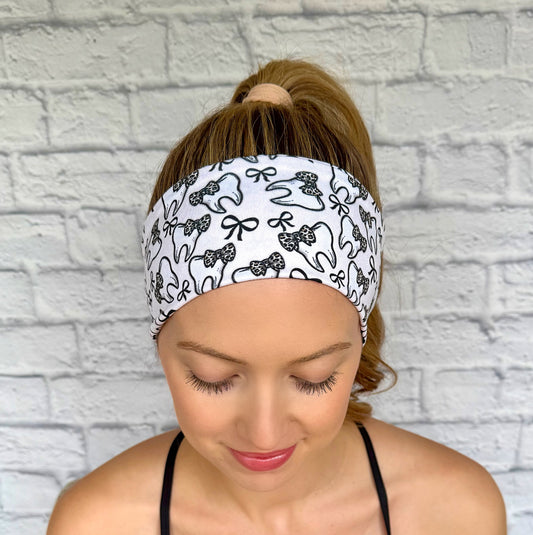 Woman with hair in ponytail wearing flat, stretchy, white headband with teeth, bow, and leopard bow print.