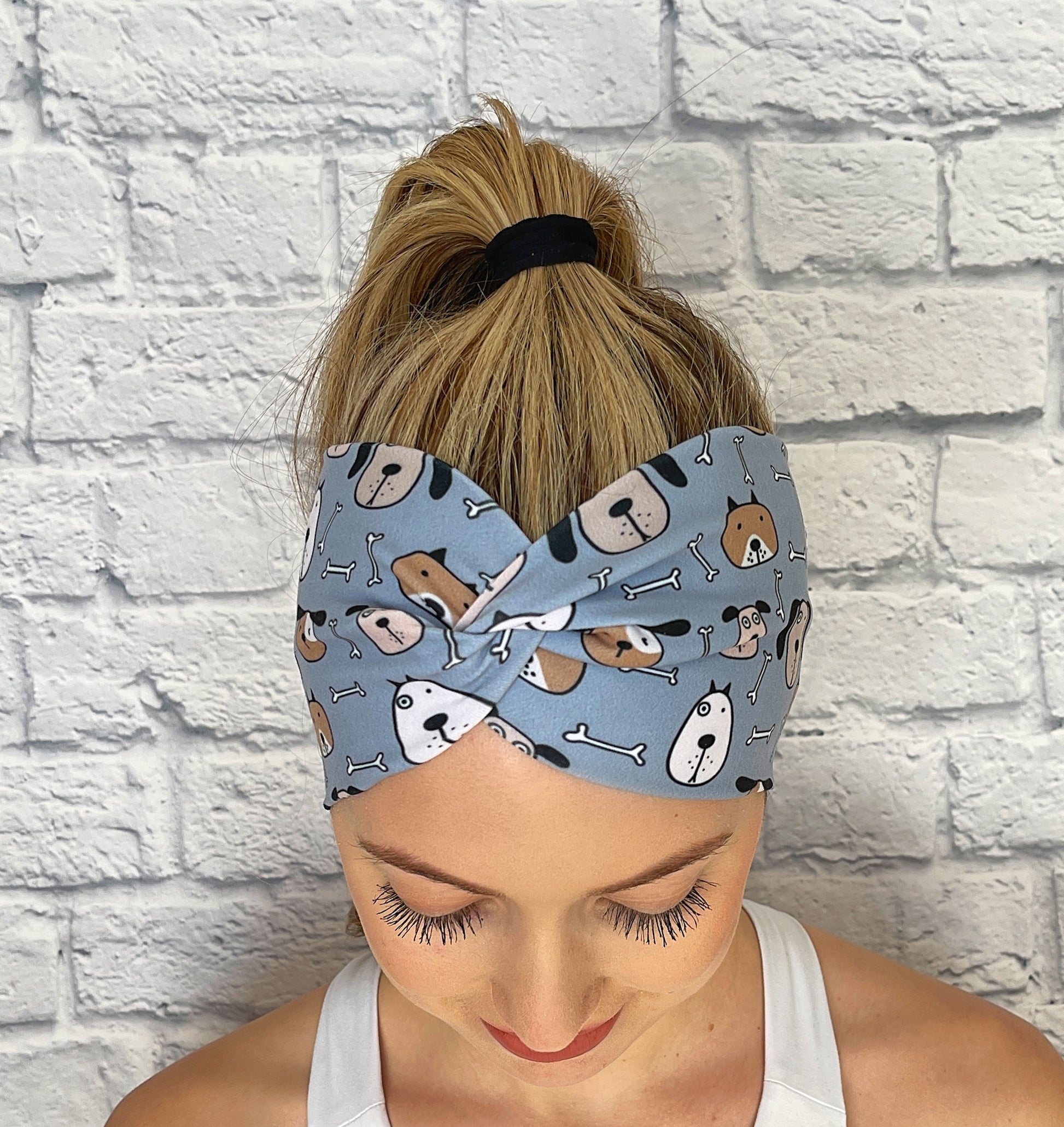 Woman with hair in ponytail wearing wide, twisted headband in blue with dog print.