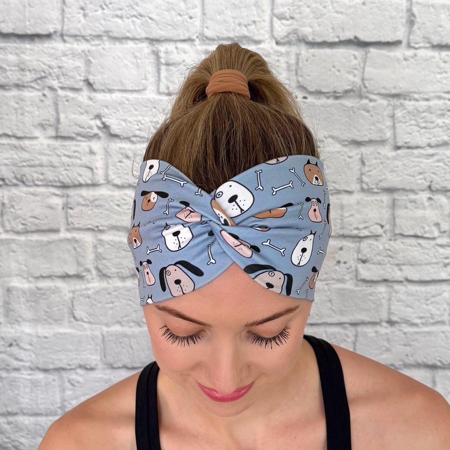 Woman with hair in ponytail wearing wide, twisted headband in blue with dog print.