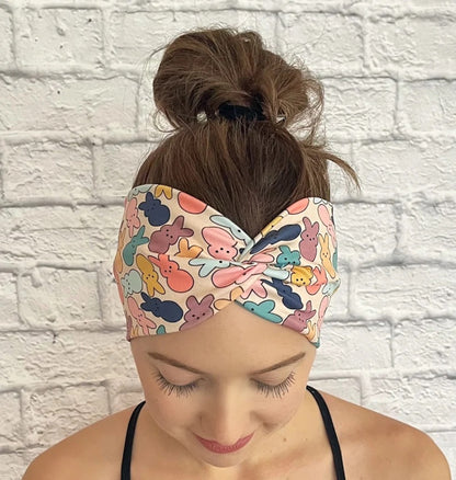 Woman with hair in bun wearing wide, twisted headband in peach/cream color with pastel print Easter bunnies.