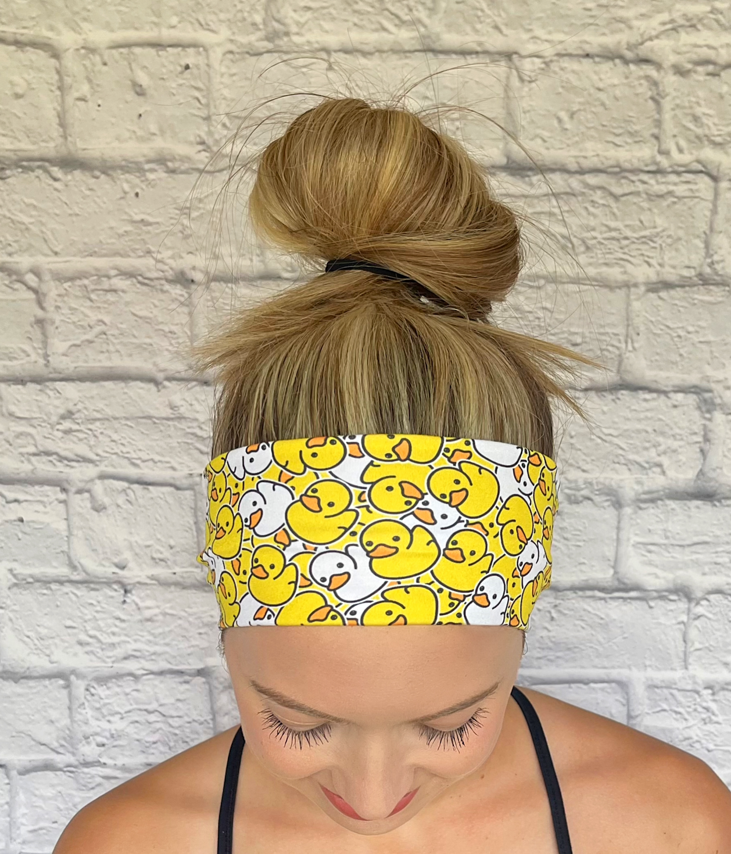 Woman with hair in bun wearing stretchy headband in yellow and white rubber duck print.