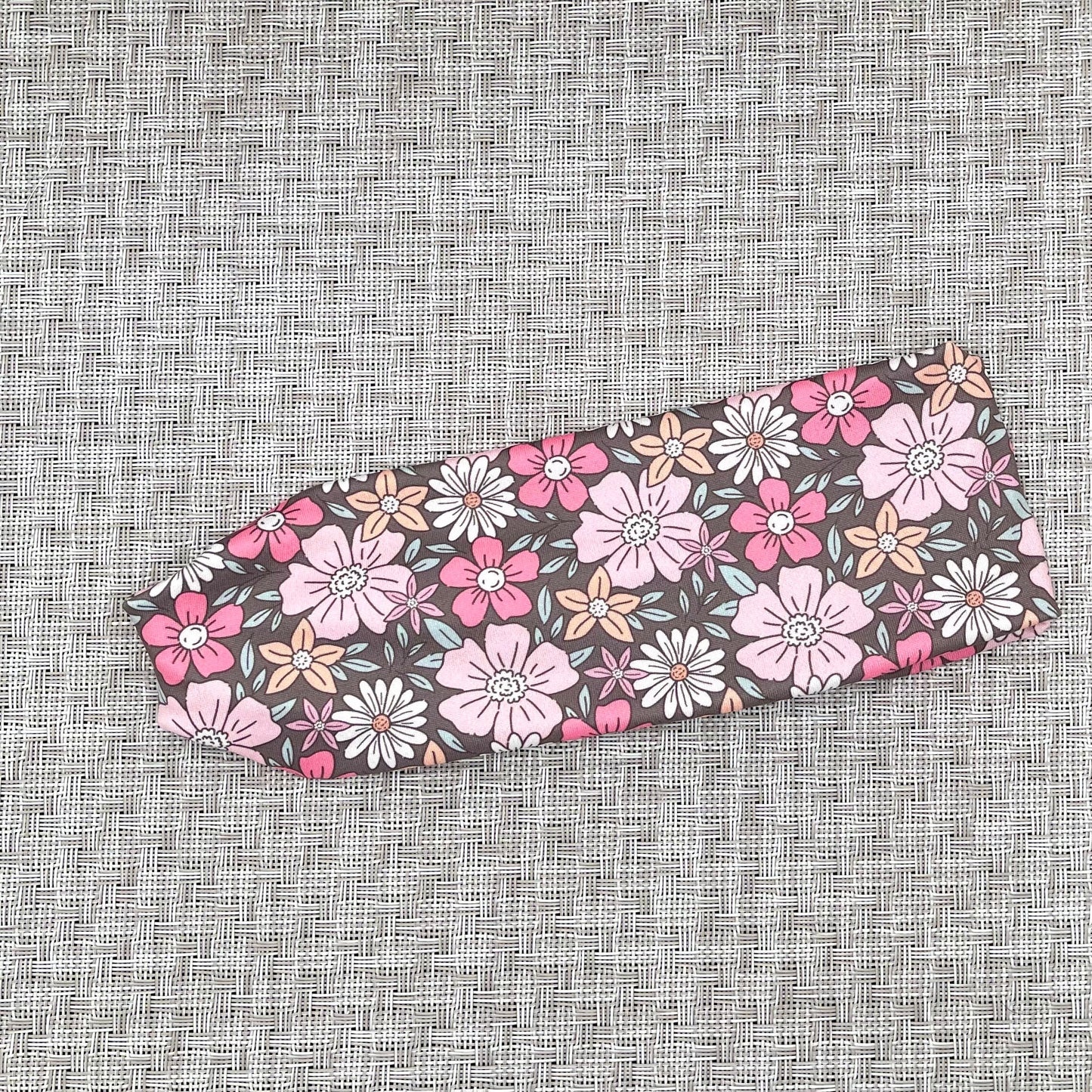 Flat, stretchy, gray headband with pink, peach, and white floral print.