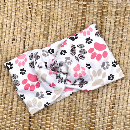 Wide, twisted headband in white with pink, gray, and black paw print.