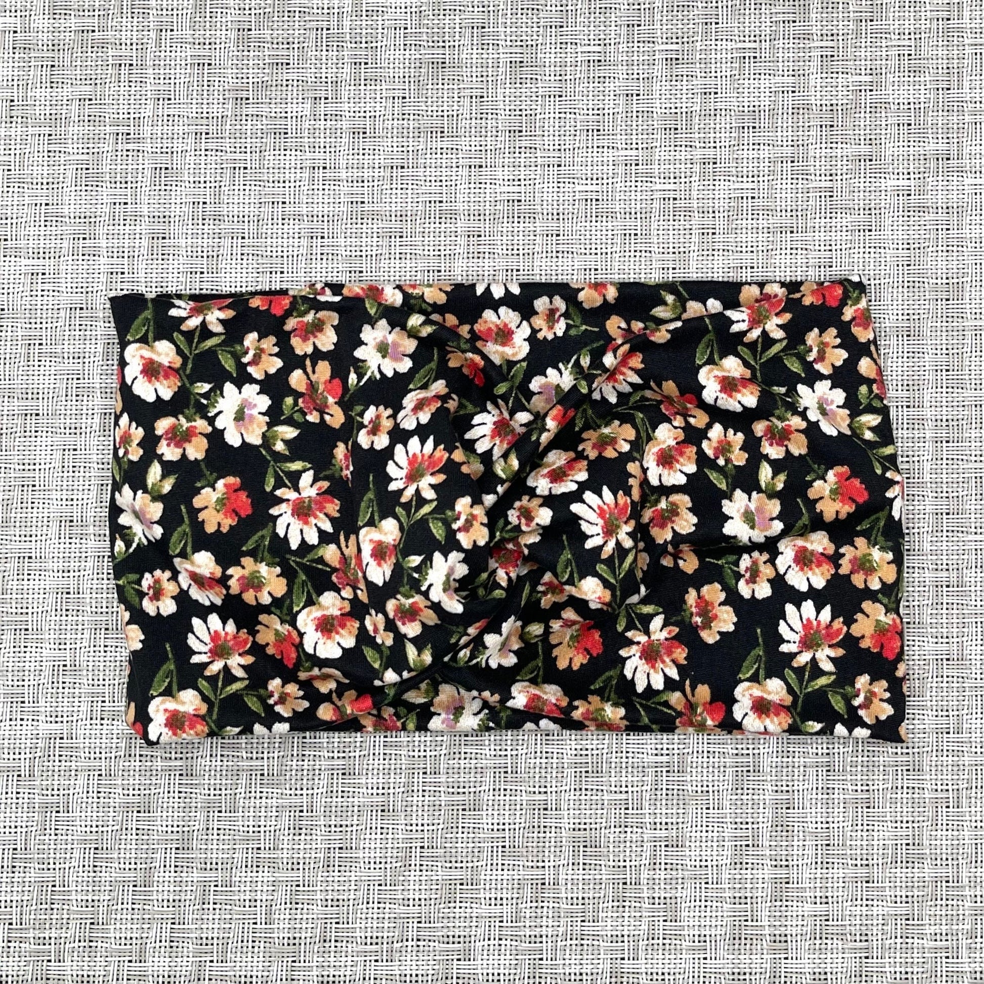 Black wide twist headband with red, yellow, and white flower print.