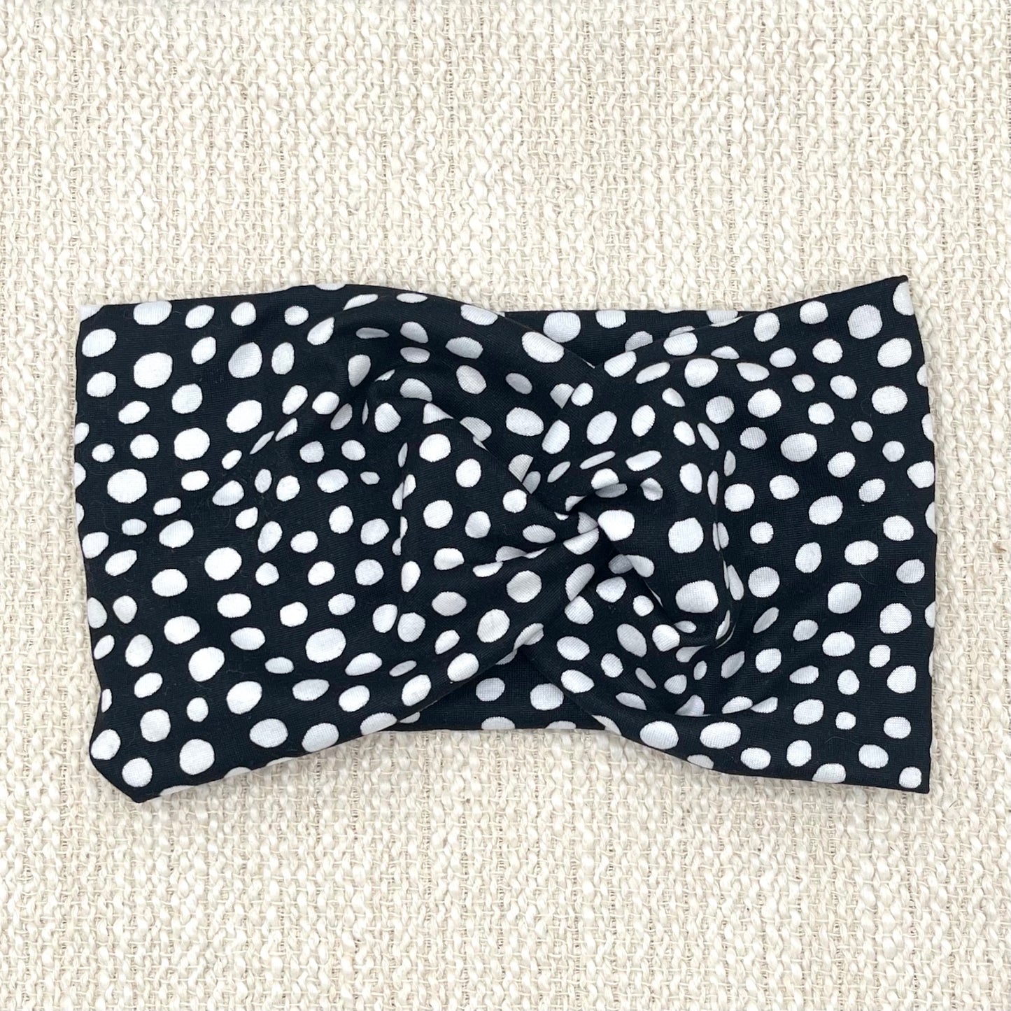 Wide, twist headband in black with white polka dot print.