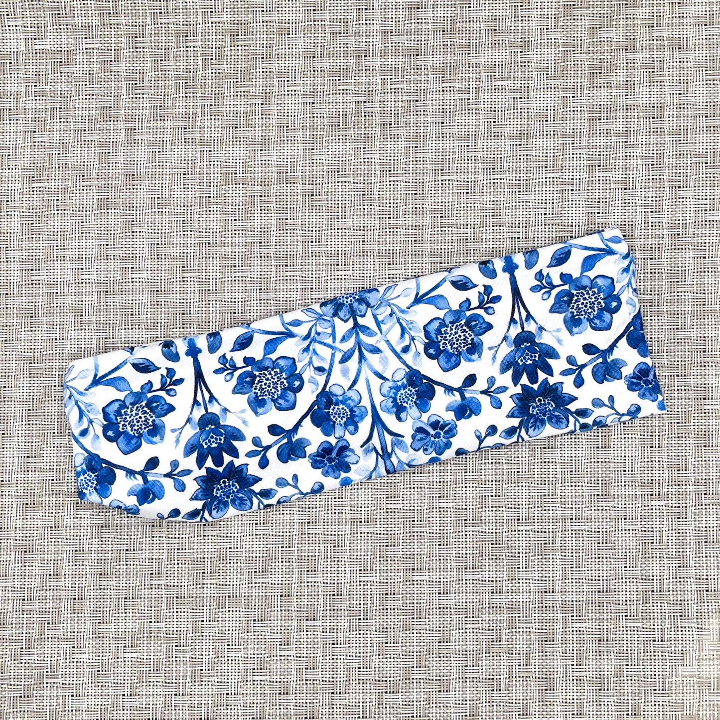 White headband with blue floral print on gray background.