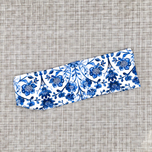 White headband with blue floral print on gray background.