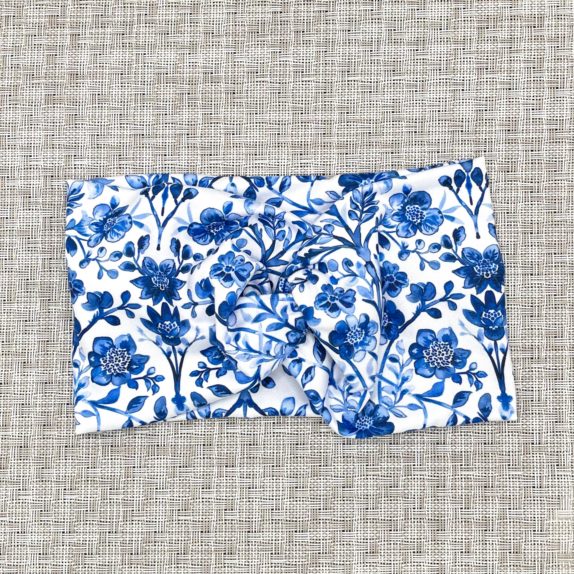 White, wide, twisted headband with blue floral print.