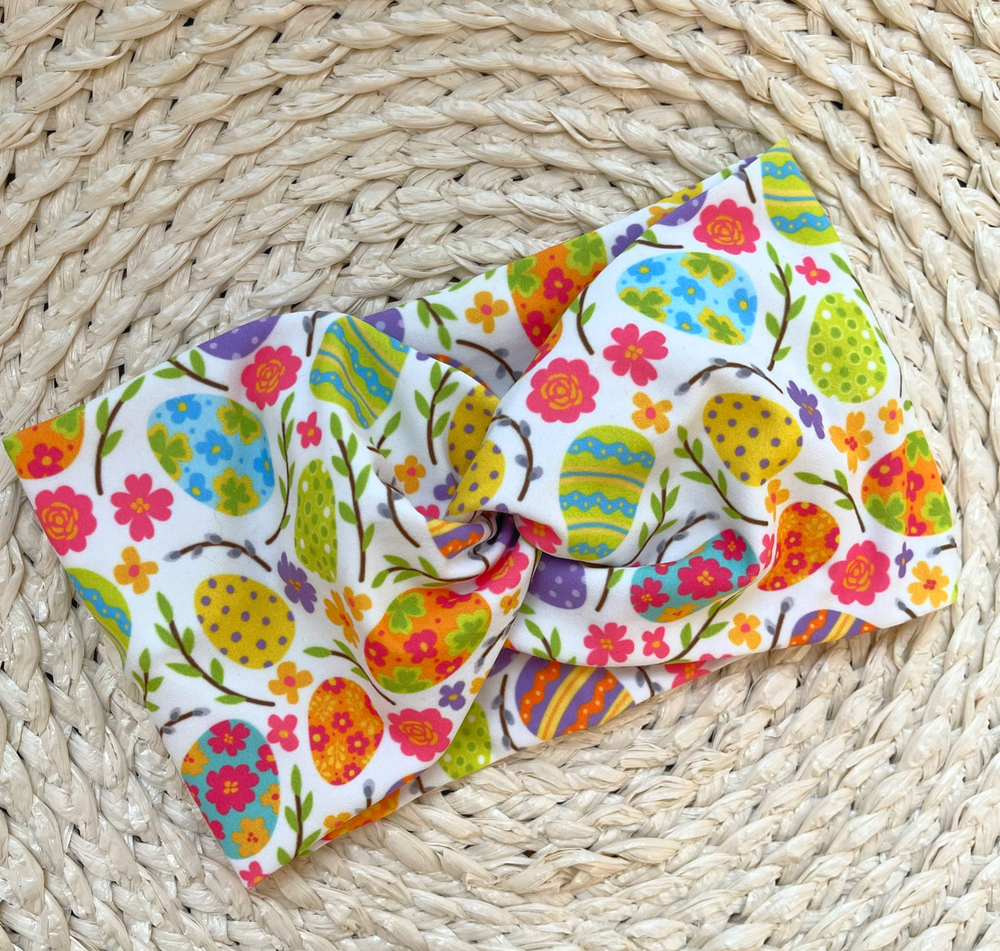 Wide, twisted headband in white with bright color Easter egg print.