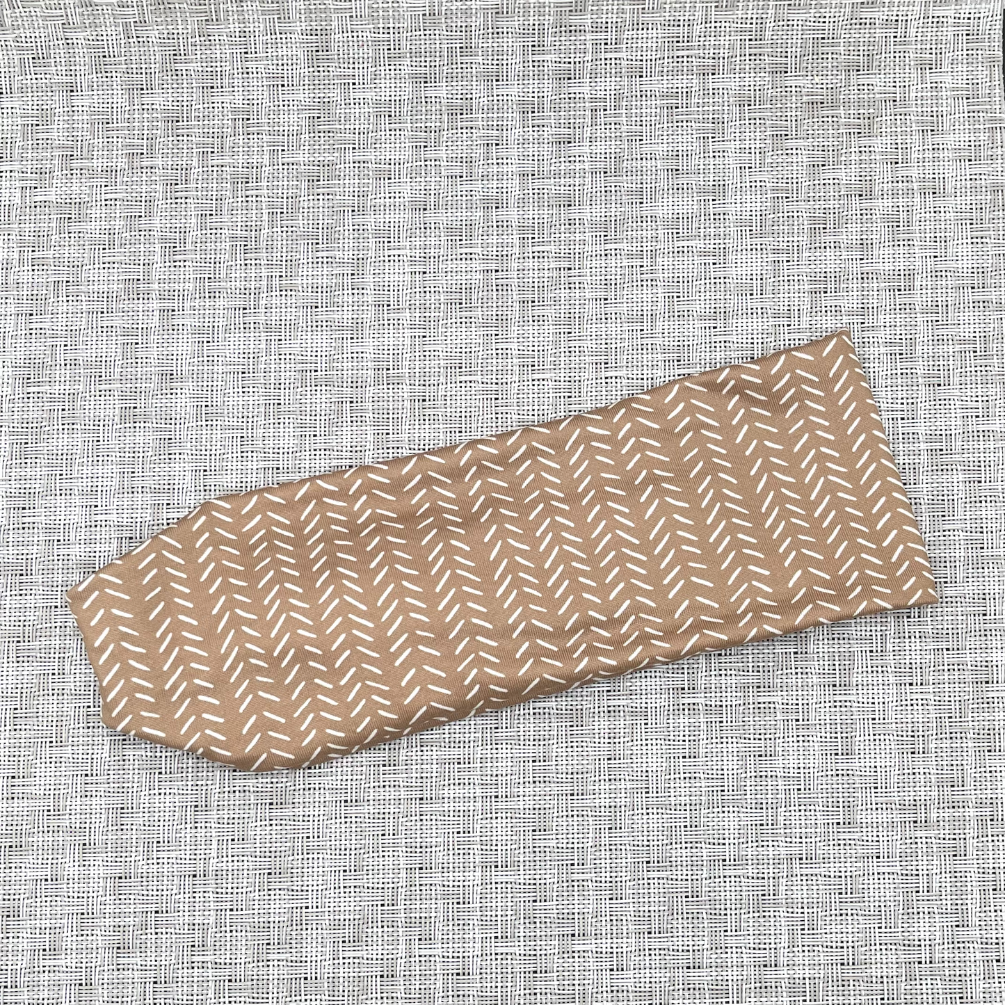 Light brown headband with small white lines printed throughout headband.