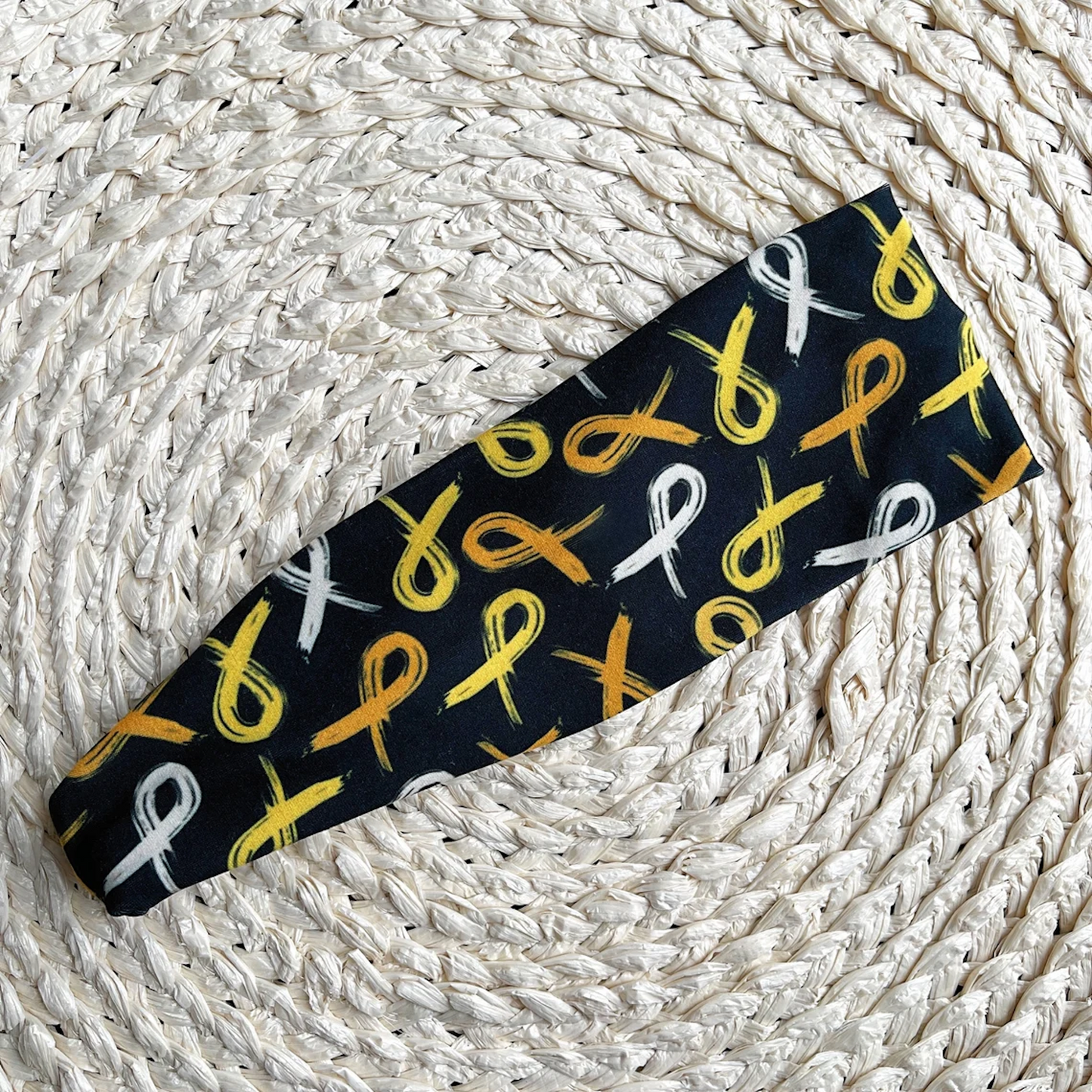 Flat, stretchy, black headband with gold ribbon print.