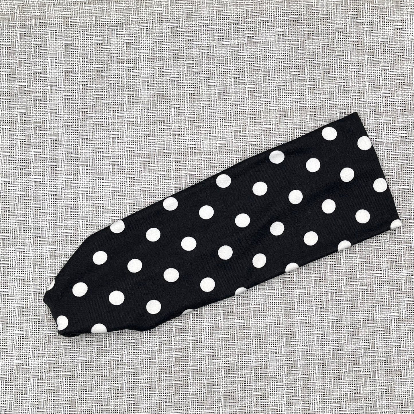 Flat, stretchy, black headband with white polka dot print.