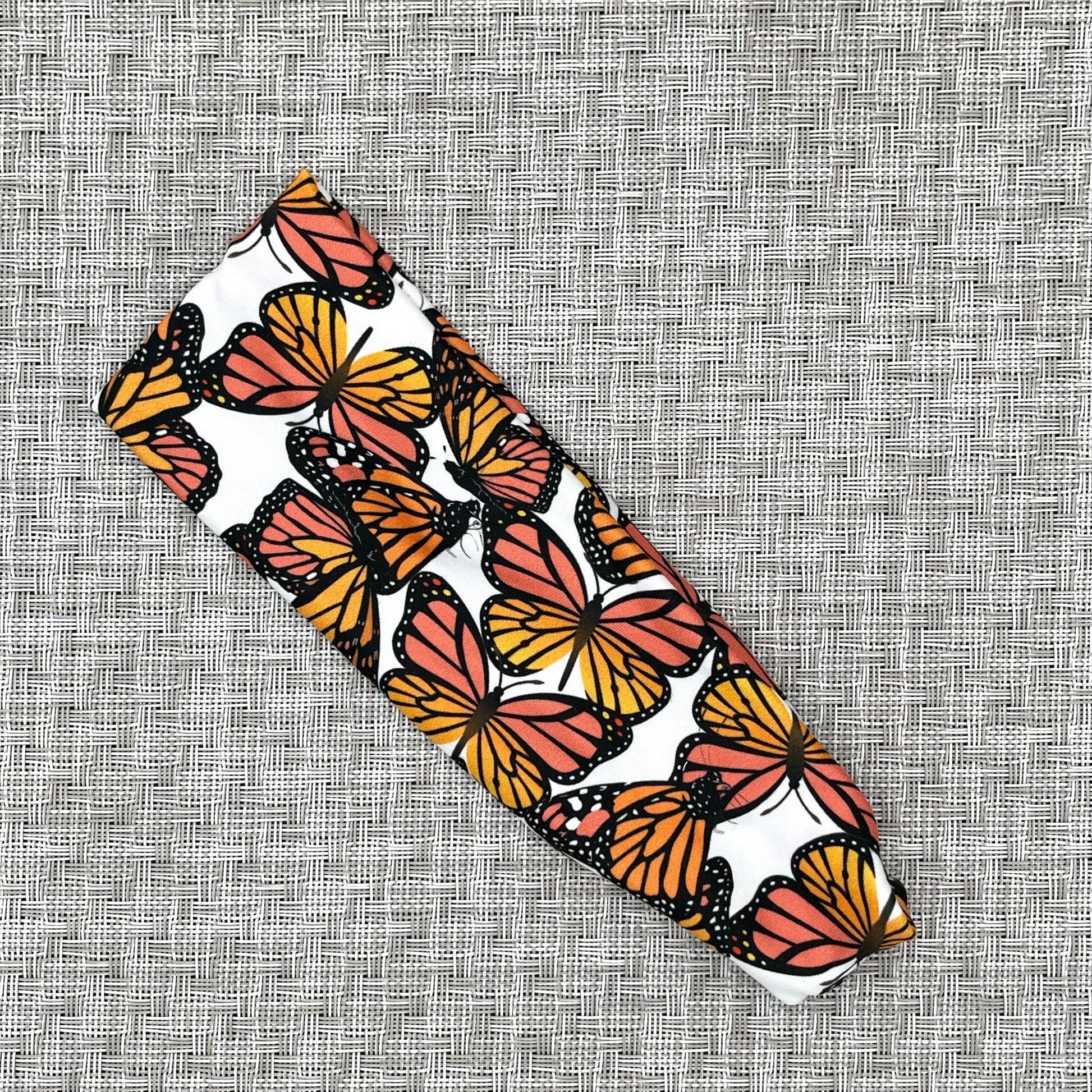 Patterned headband with orange and black butterfly design on a textured gray background