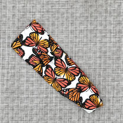 Patterned headband with orange and black butterfly design on a textured gray background