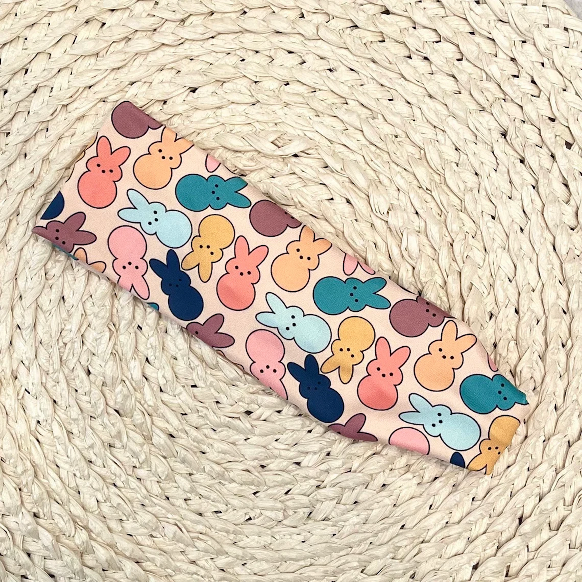 Flat, stretchy headband in cream/peach color with pastel print Easter bunnies.