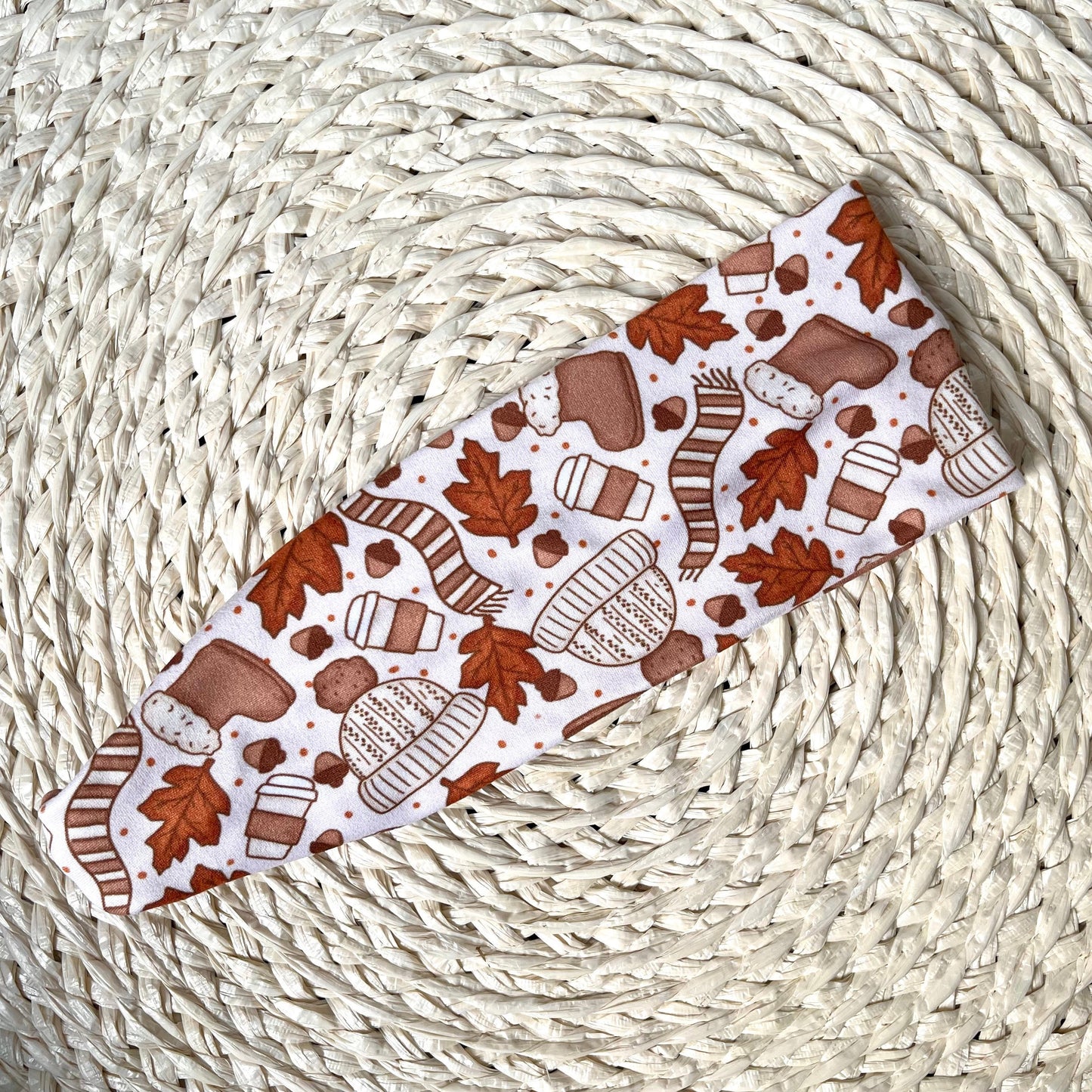 Patterned headband with autumn leaves and cozy items on a woven surface