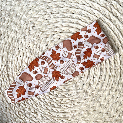 Patterned headband with autumn leaves and cozy items on a woven surface