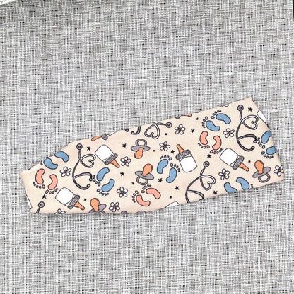 Tan headband with baby-themed pattern on a textured gray background