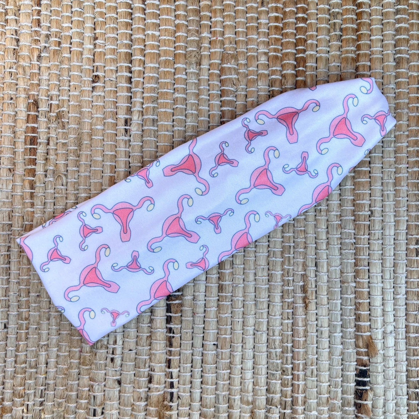 Flat, stretchy, white headband with uterus print.