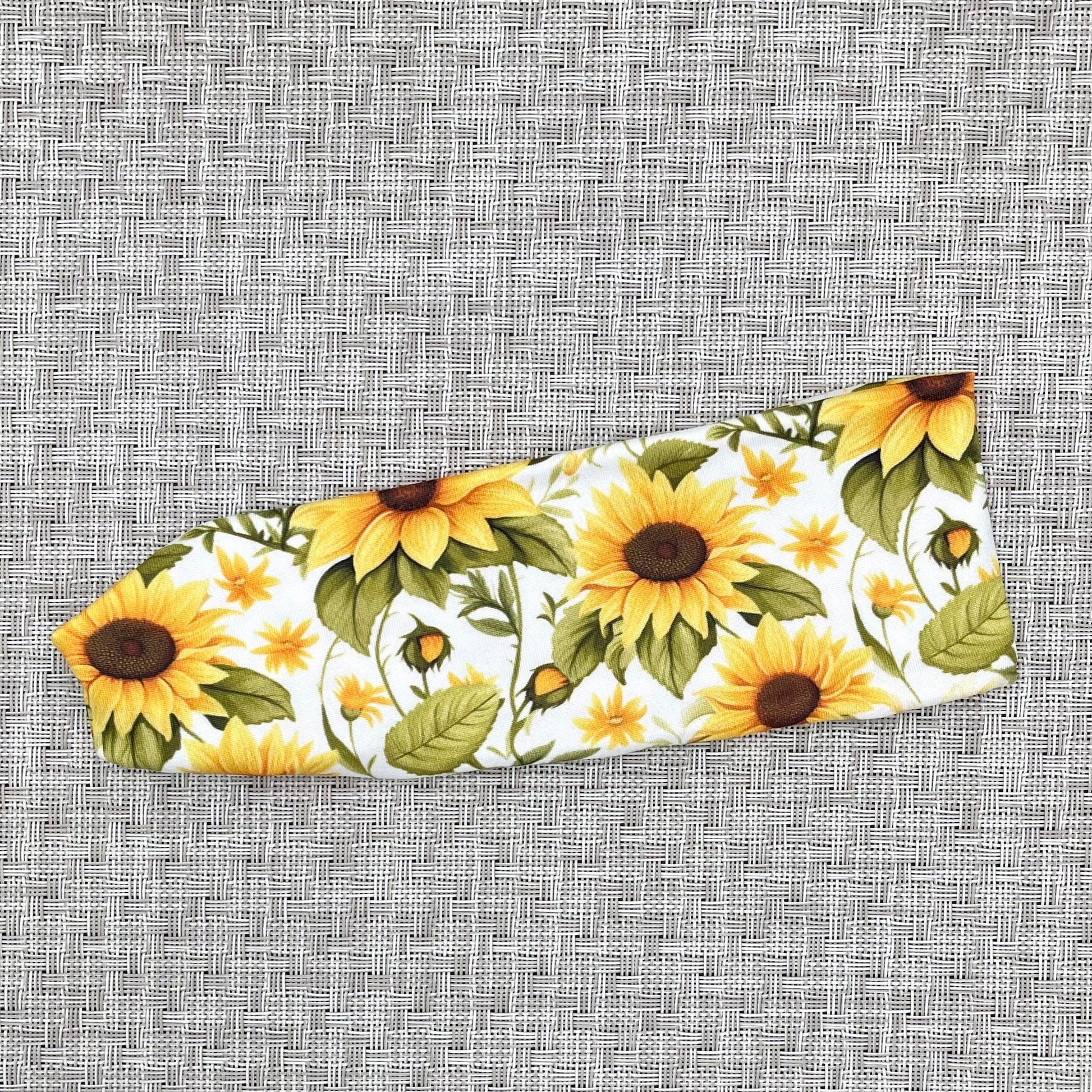 White stretchy headband with sunflower print.
