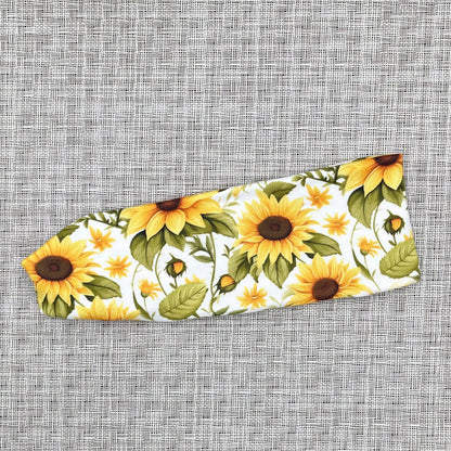 White stretchy headband with sunflower print.