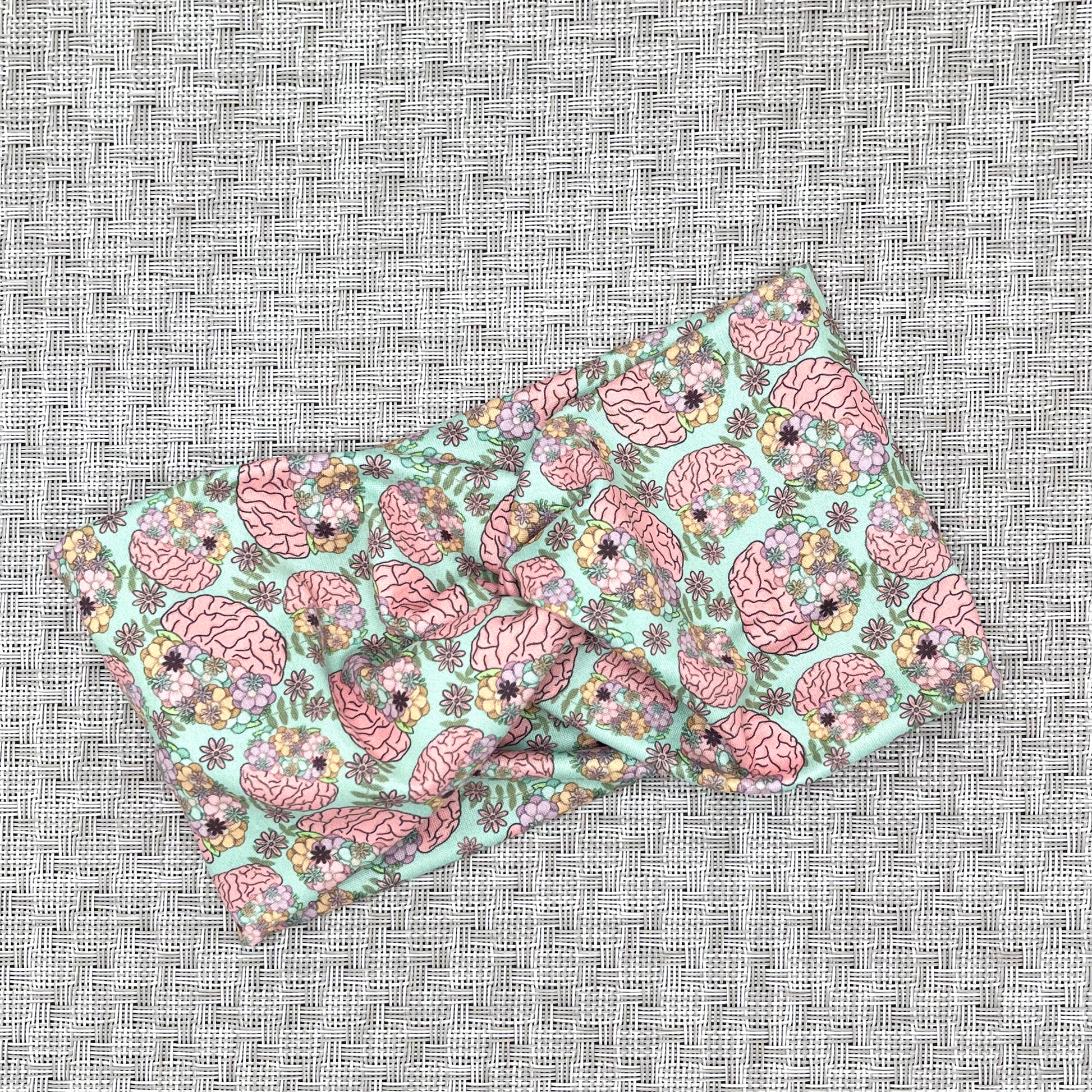 Wide, twisted headband in mint green color with brain and flower print.