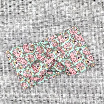 Wide, twisted headband in mint green color with brain and flower print.