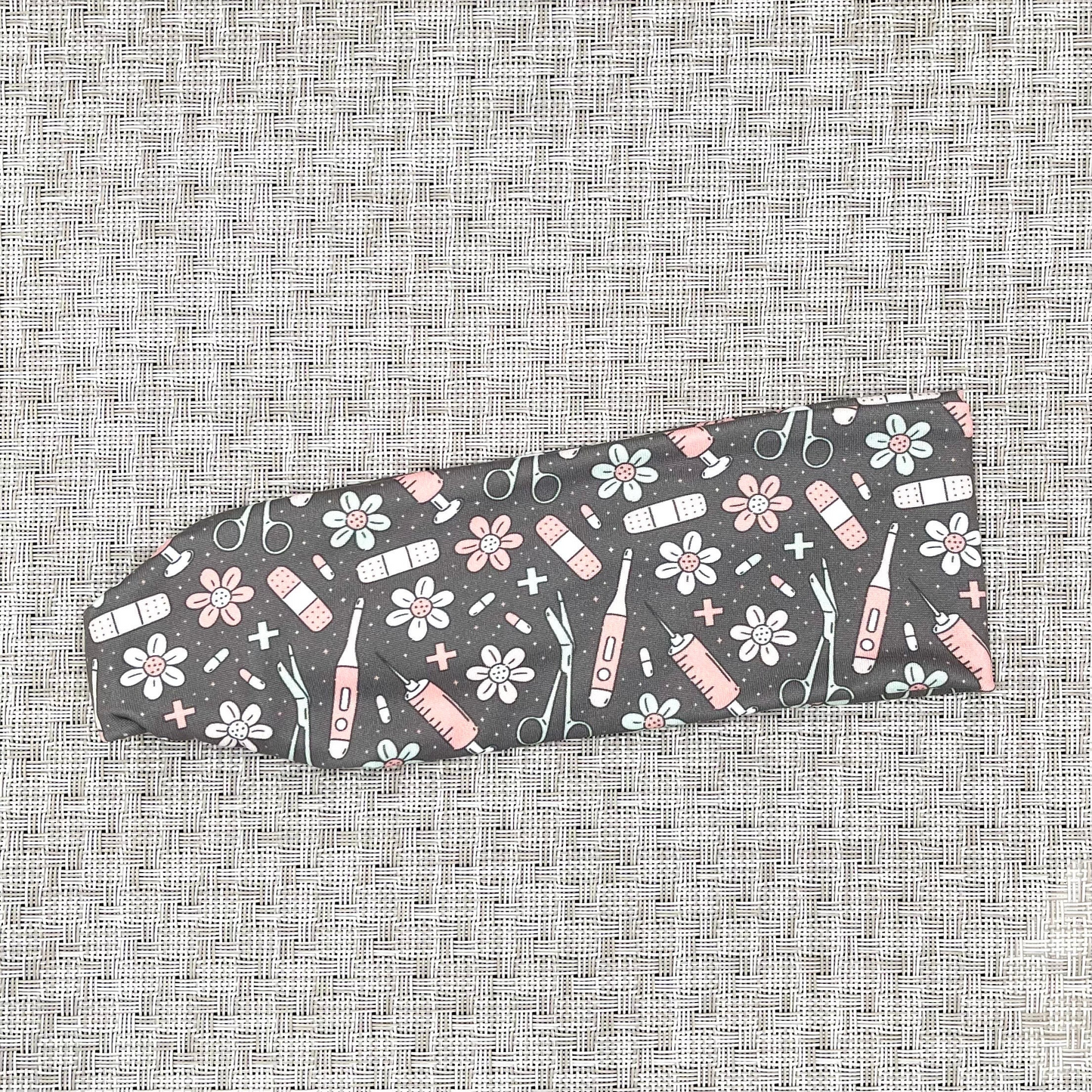 Stretchy, gray headband with pink, white, and seafoam green medical and floral theme print.