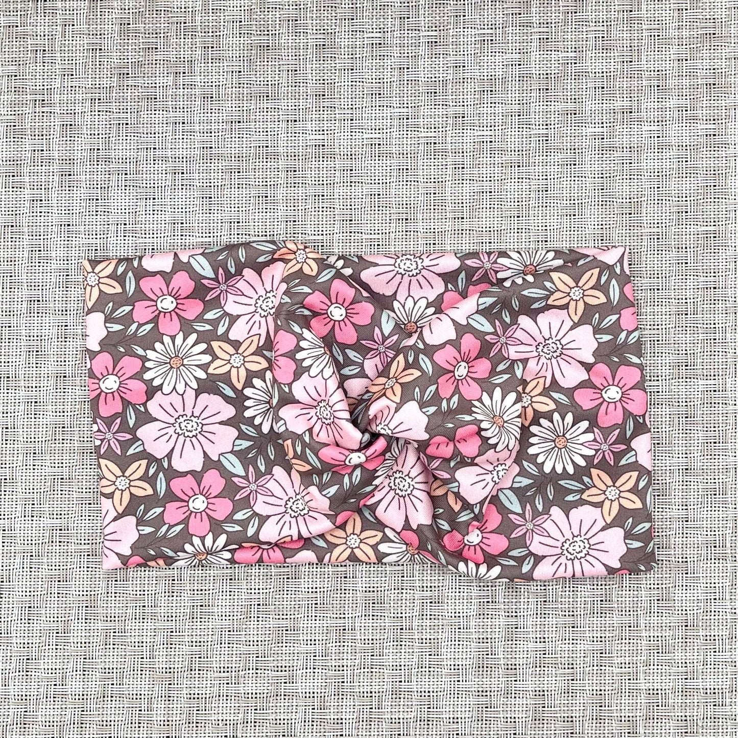 Wide, twisted headband in gray with pink, peach, and white floral print.