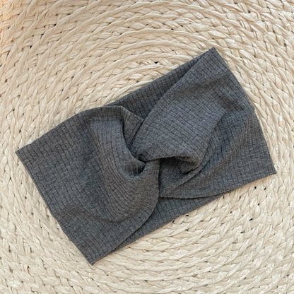 Wide, twisted headband in gray ribbed fabric.