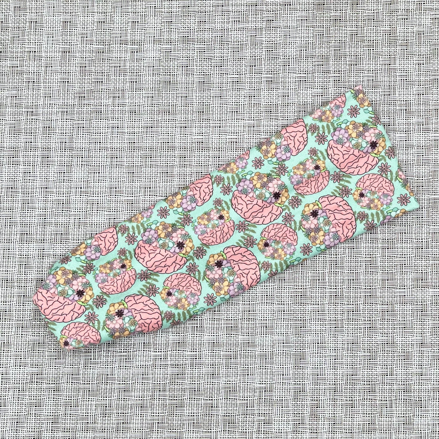 Stretchy, mint green color headband with brain and floral print.