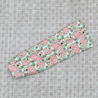 Stretchy, mint green color headband with brain and floral print.