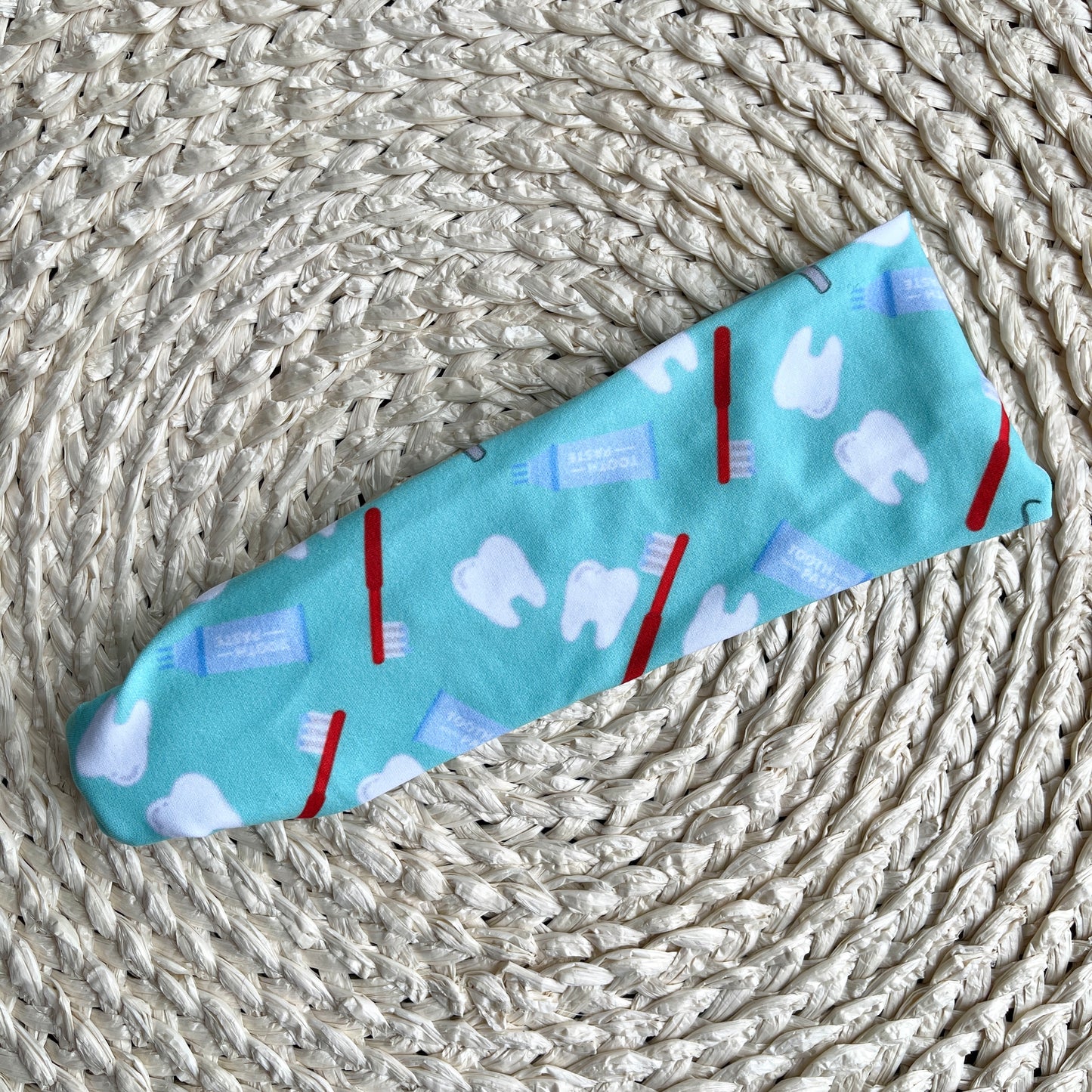 Flat, stretchy headband in mint blue with dental theme print.