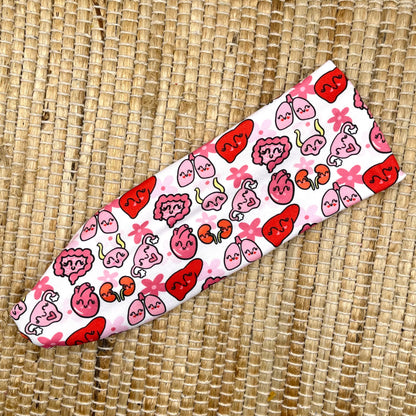 Stretchy, white headband with pink and red organ theme print.