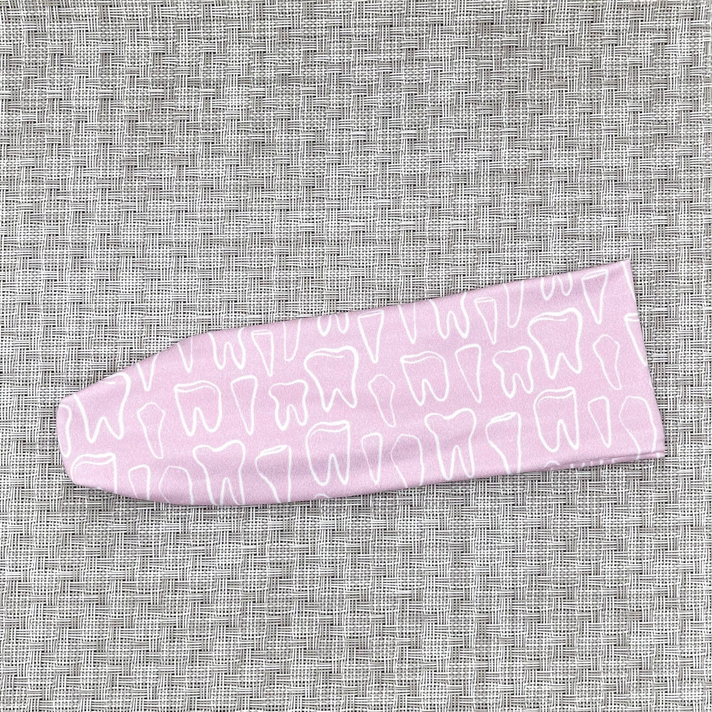 Stretchy, light pink headband with white teeth print.