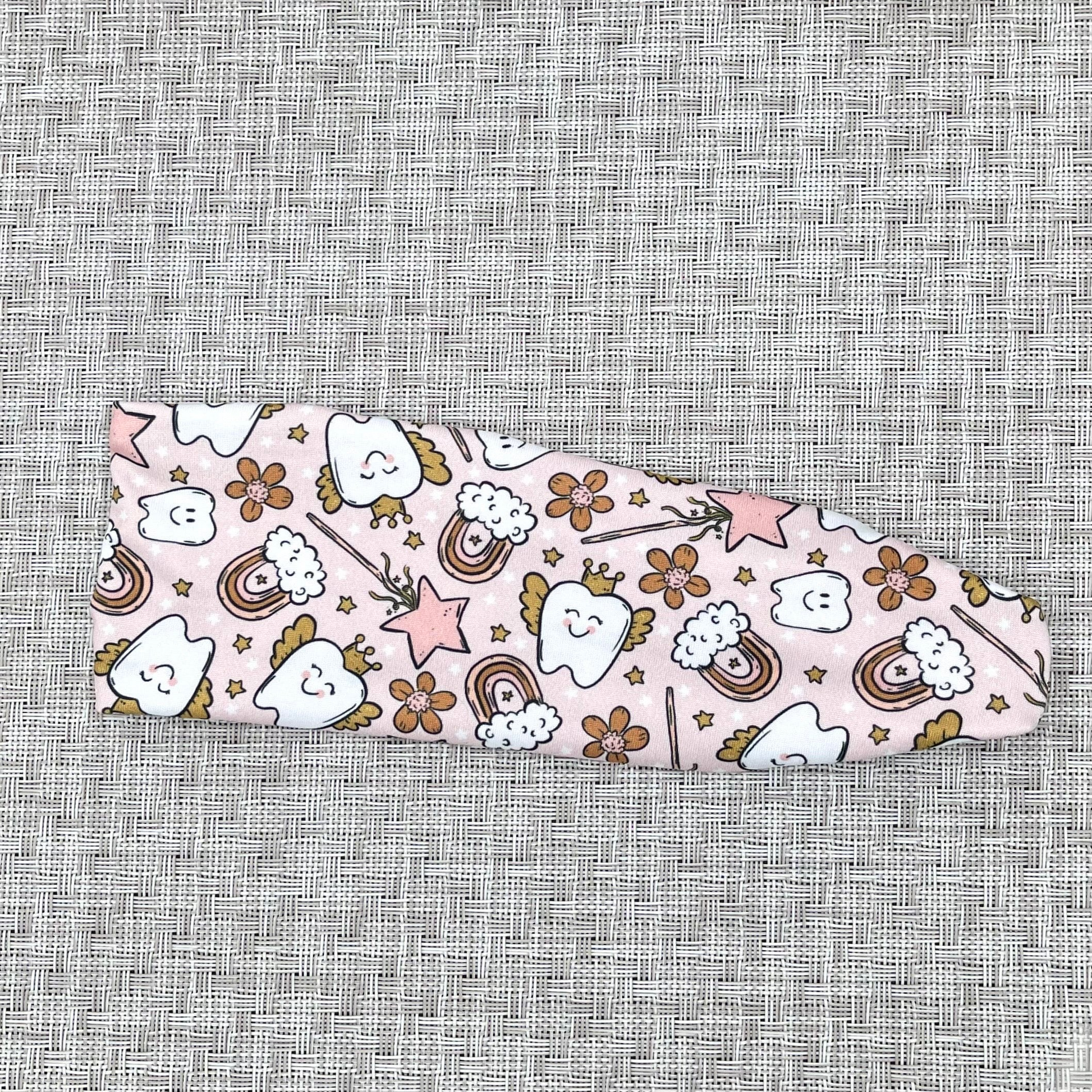 Light pink stretchy headband with teeth and tooth fairly theme print.