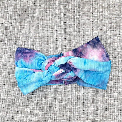Sailor knot style headband in ribbed fabric with purple and blue tie dye print.