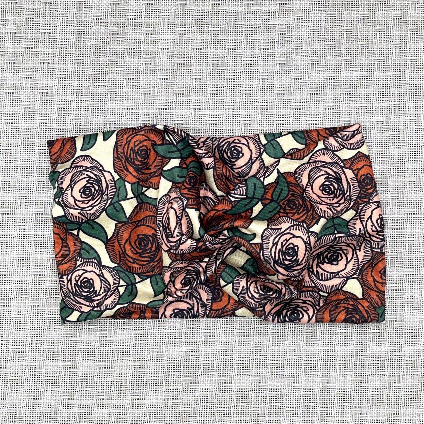 Wide, twisted headband in cream with red and pink rose print.