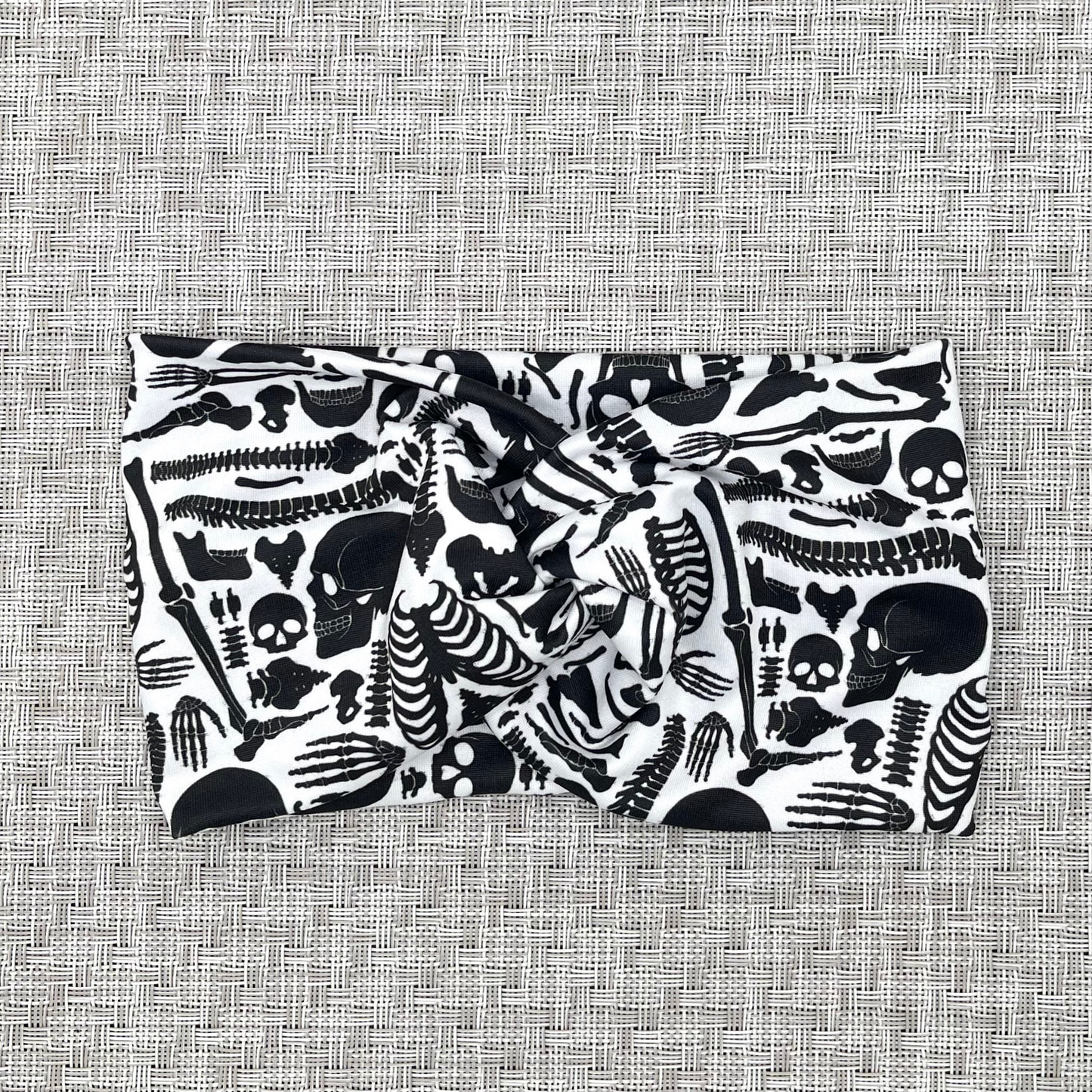 Wide twist headband with black skeleton print. 