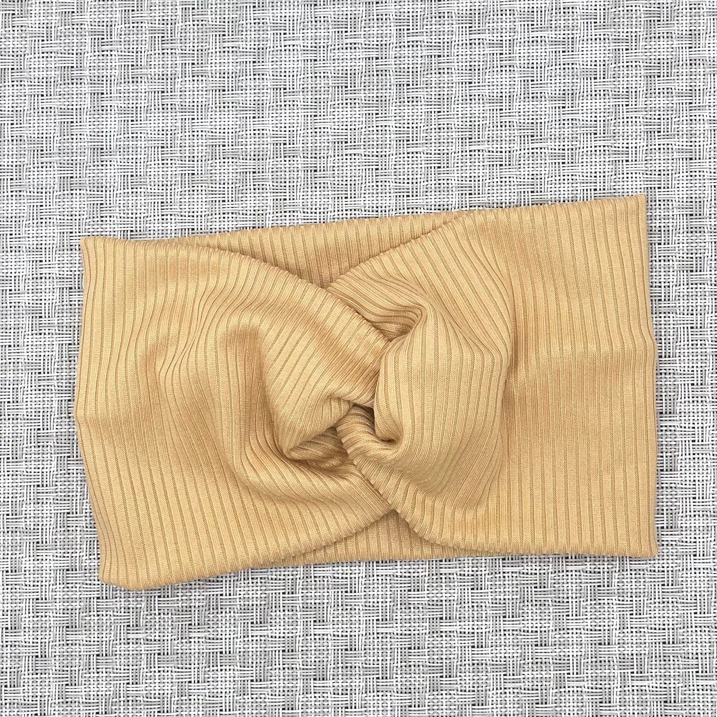 Wide, twisted headband with tan ribbed fabric.